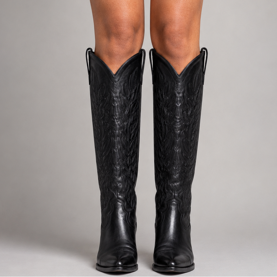 Black knee-high boots worn by a person on a gray background